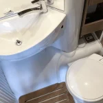 Detalle del baño de una autocaravana con lavabo e inodoro, ideal para destacar el equipamiento completo en el alquiler de autocaravanas en Sevilla.