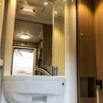 Lavabo moderno con espejo amplio en el baño de una autocaravana, ideal para quienes buscan comodidad en el alquiler de autocaravanas en Sevilla.