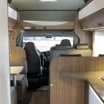 Vista general del interior de una autocaravana con cocina, comedor y zona de conducción, ideal para alquiler de autocaravanas en Sevilla.