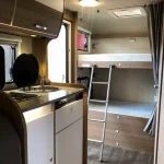 Interior de autocaravana con cocina y literas, perfecta para mostrar las ventajas del alquiler de autocaravanas en Sevilla.