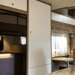 Interior moderno de autocaravana con zona de comedor, armarios y detalles de diseño, ideal para mostrar opciones de alquil